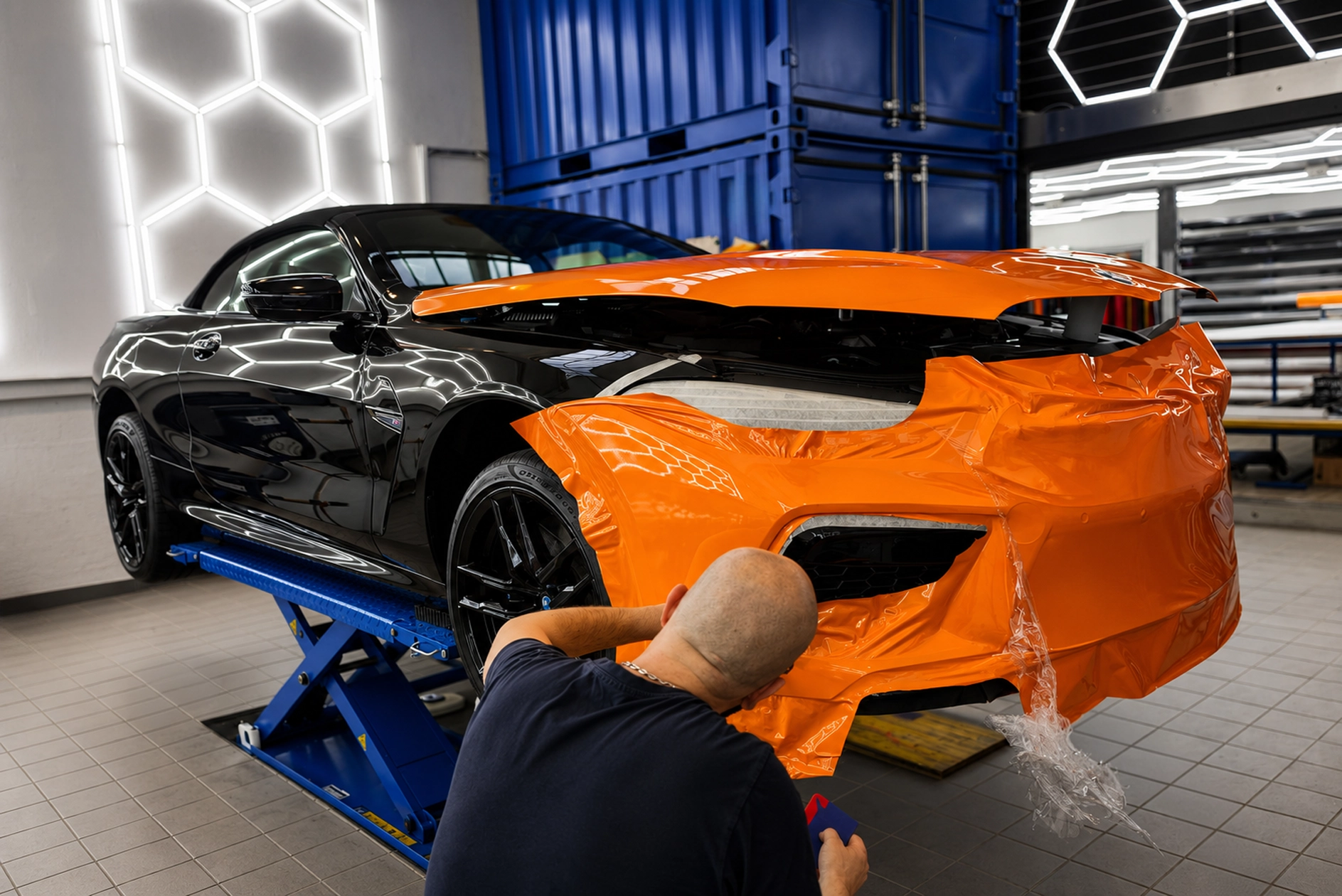 Pose d’un covering orange sur l’avant d’un véhicule dans l’atelier Décora Publicité à Genève
